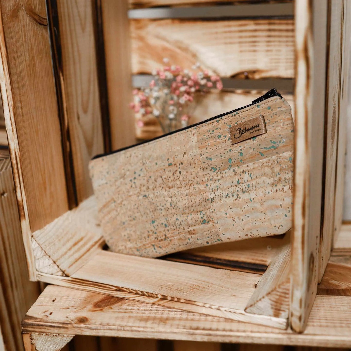 Kleine grüne Kosmetiktasche aus Kork auf Holzregal.