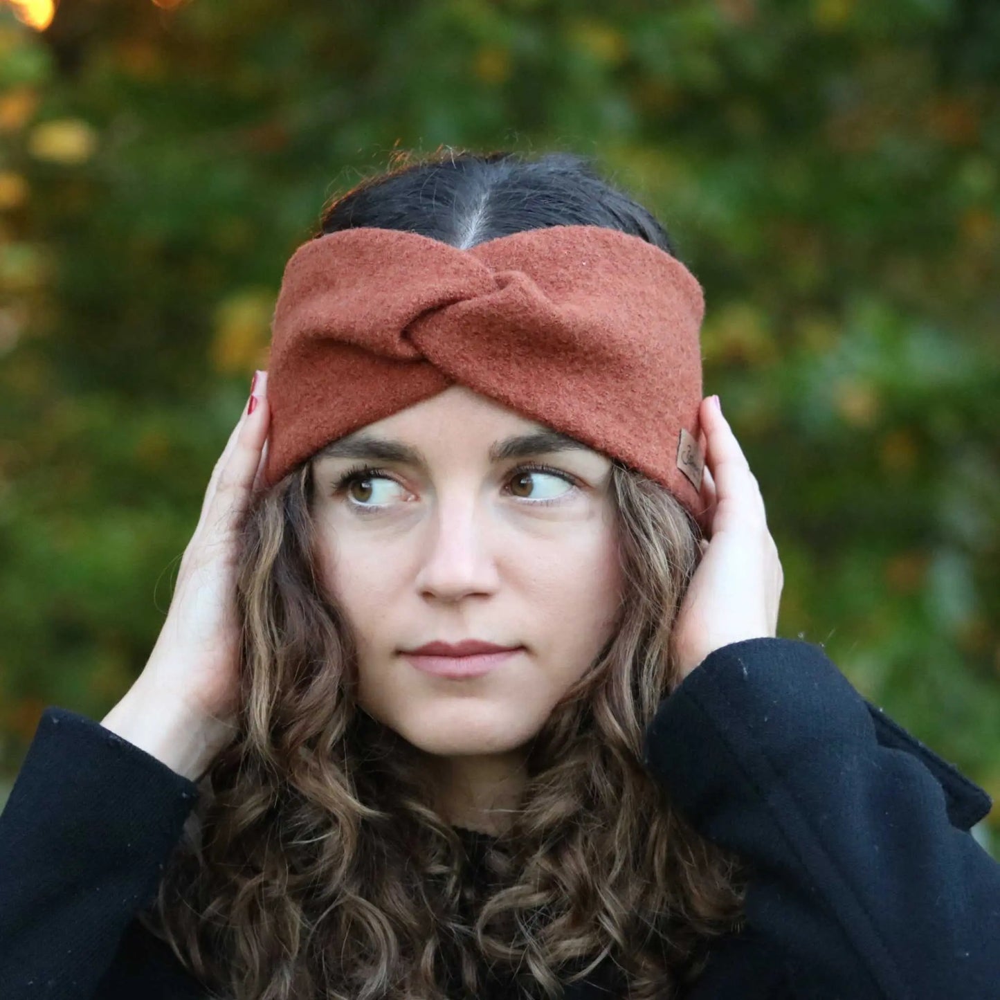 Wollwalk Stirnband in rostrot worn outdoors for warmth and style.