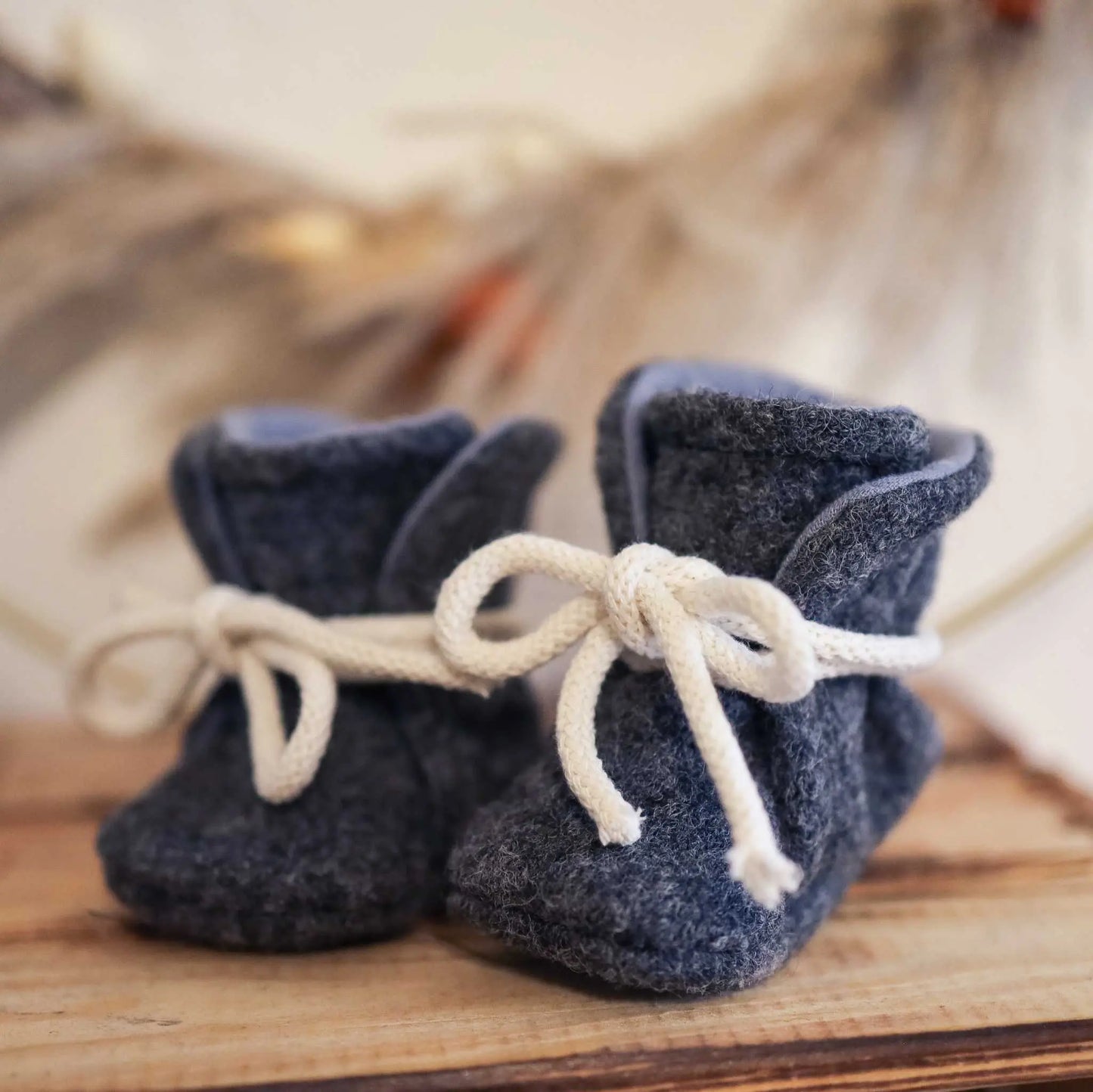 Babyschühchen aus Wollwalk in Anthrazit auf Holzuntergrund
