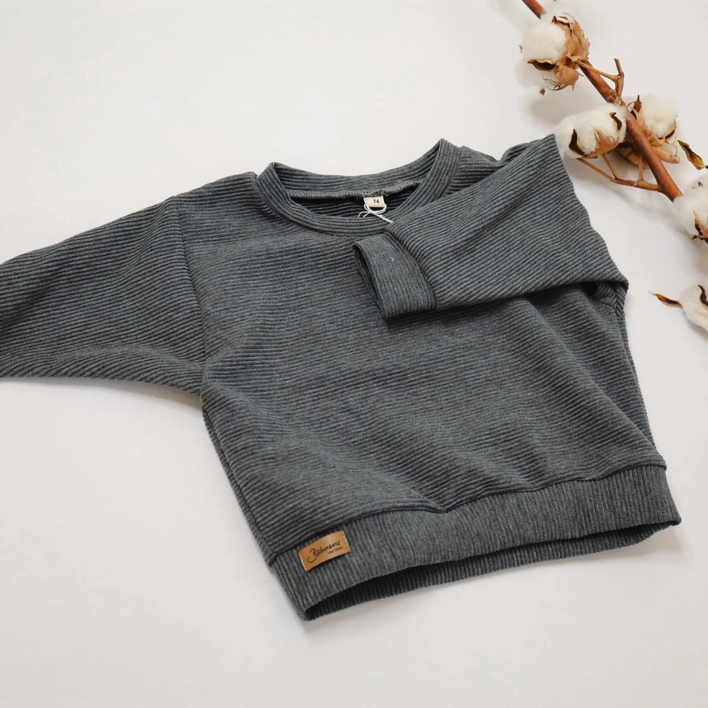 Oversize Pullover aus RIB in dark gray, displayed with cotton plant accents.