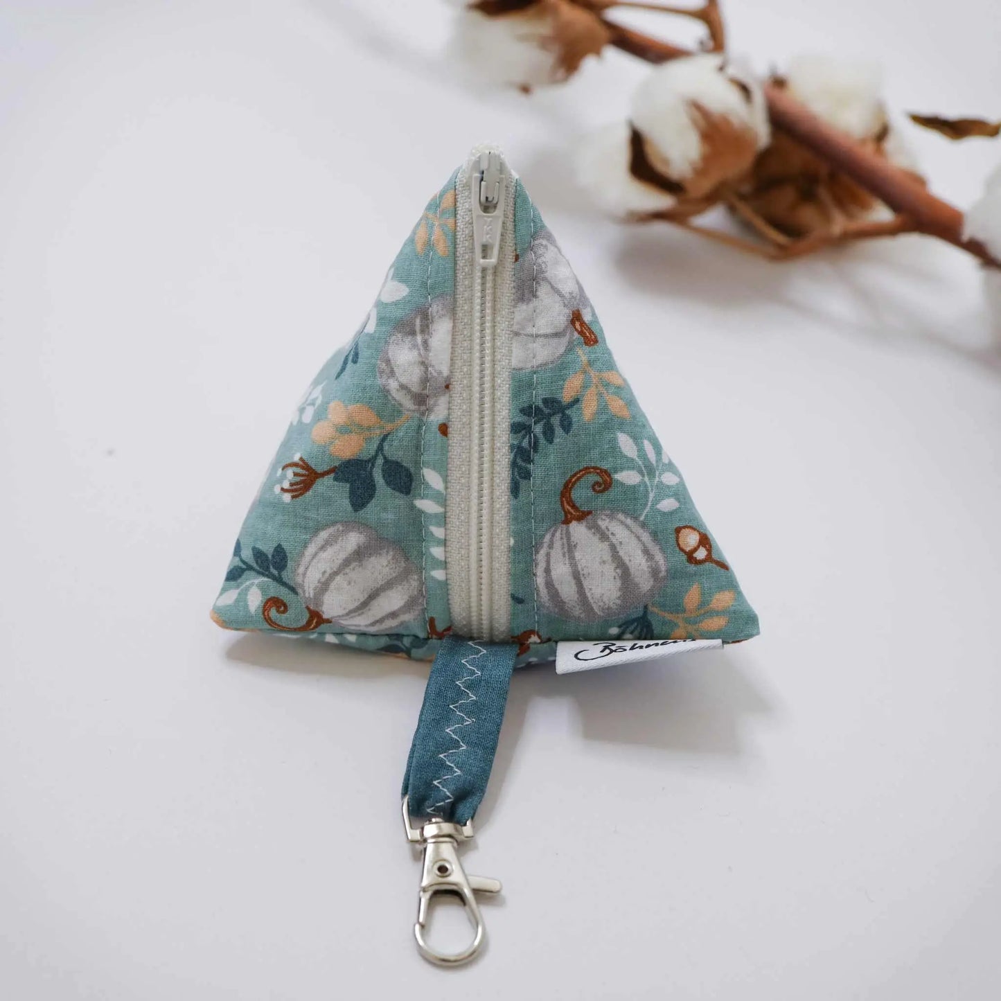Dreieckige Schnickschnack-Tasche mit Kürbis-Muster und Reissverschluss auf hellem Hintergrund.