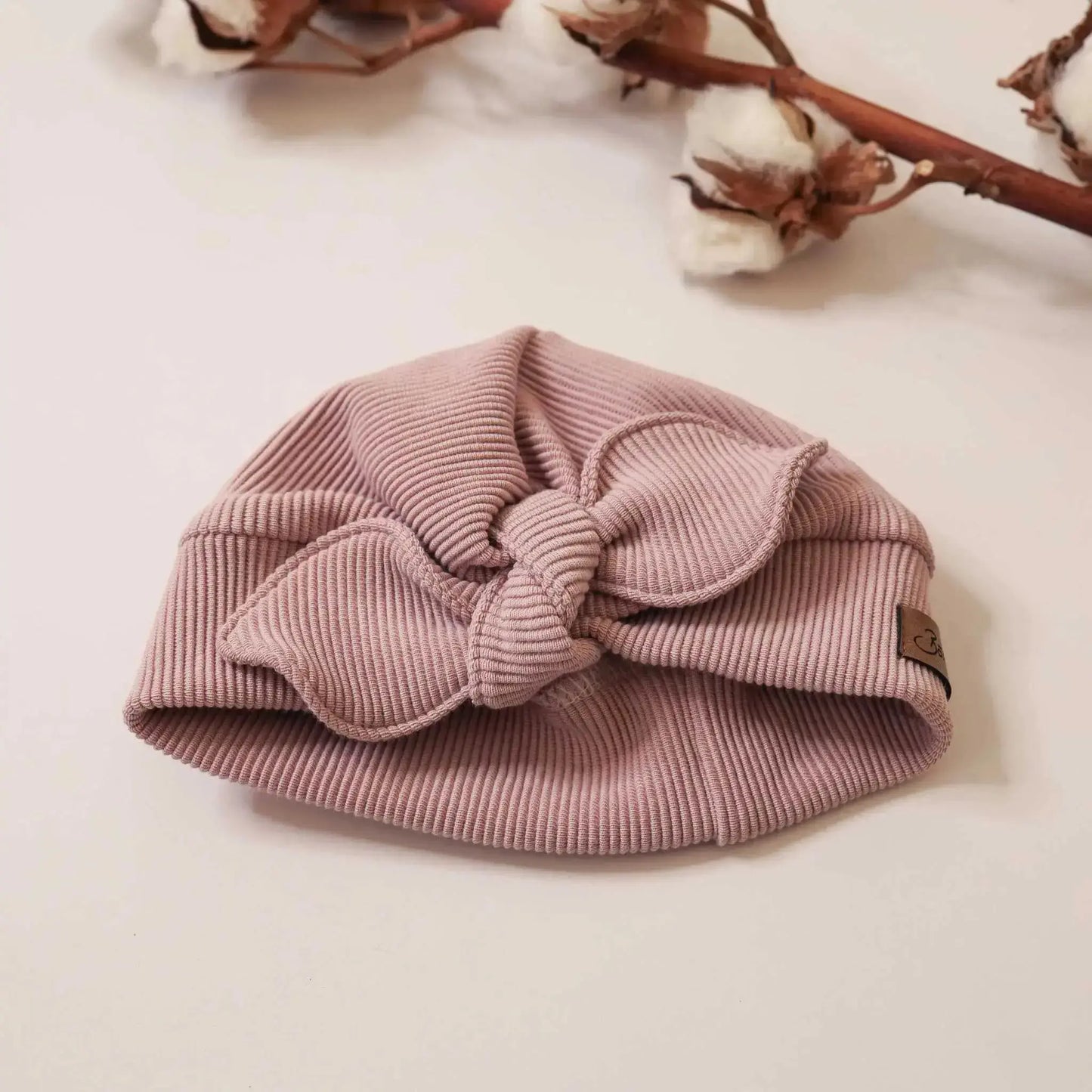 Pink turban hat with bow on neutral background.