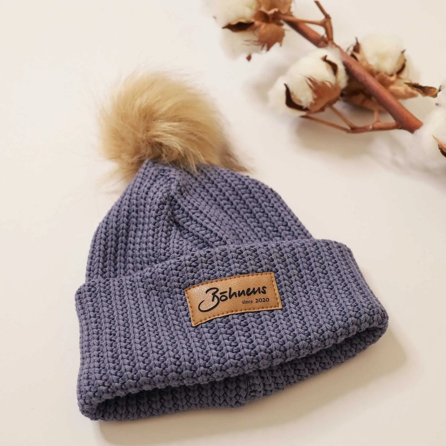 Blue chunky knit beanie with pom-pom, ideal for cold weather.