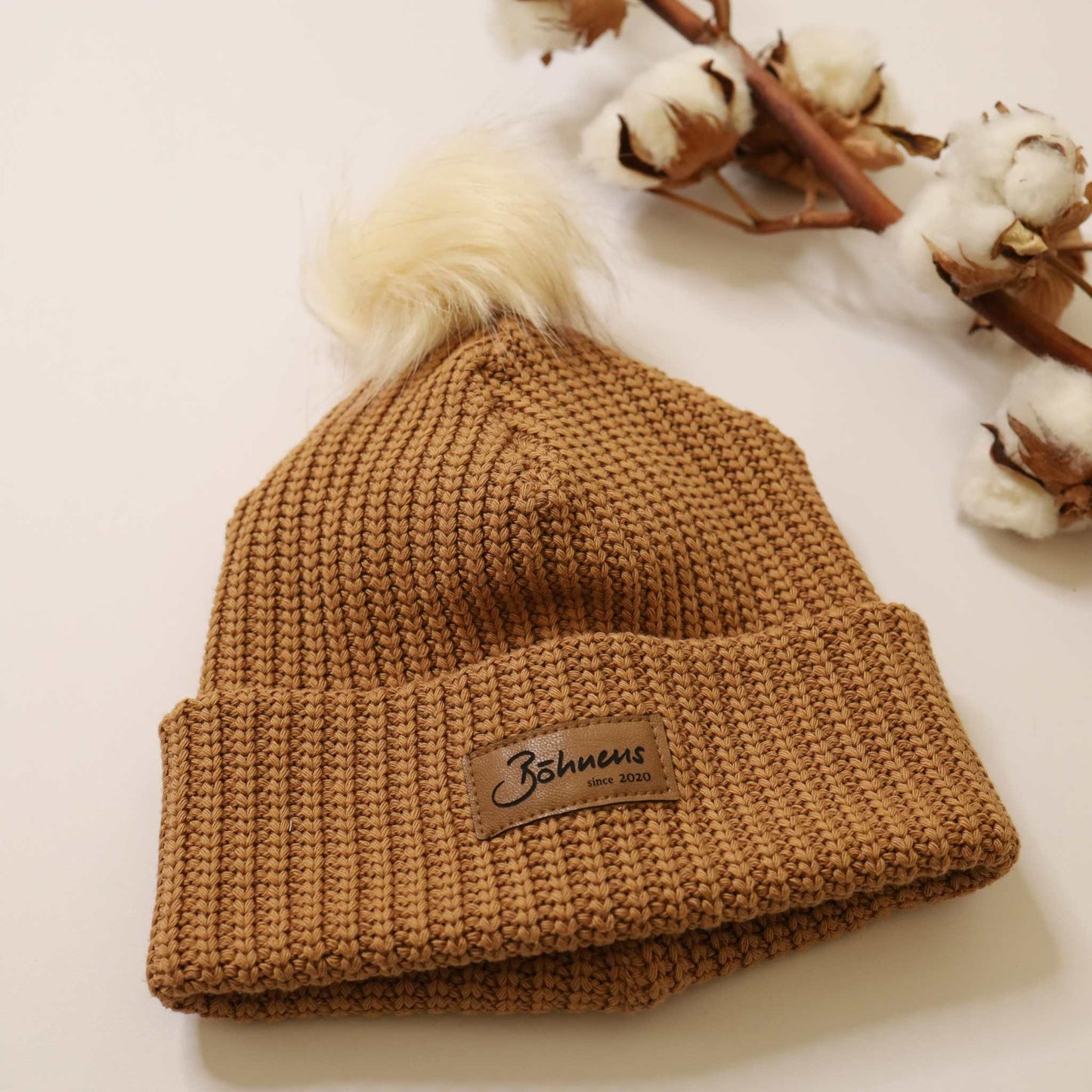 Trendy camel-colored chunky knit beanie with pom-pom for cold days.