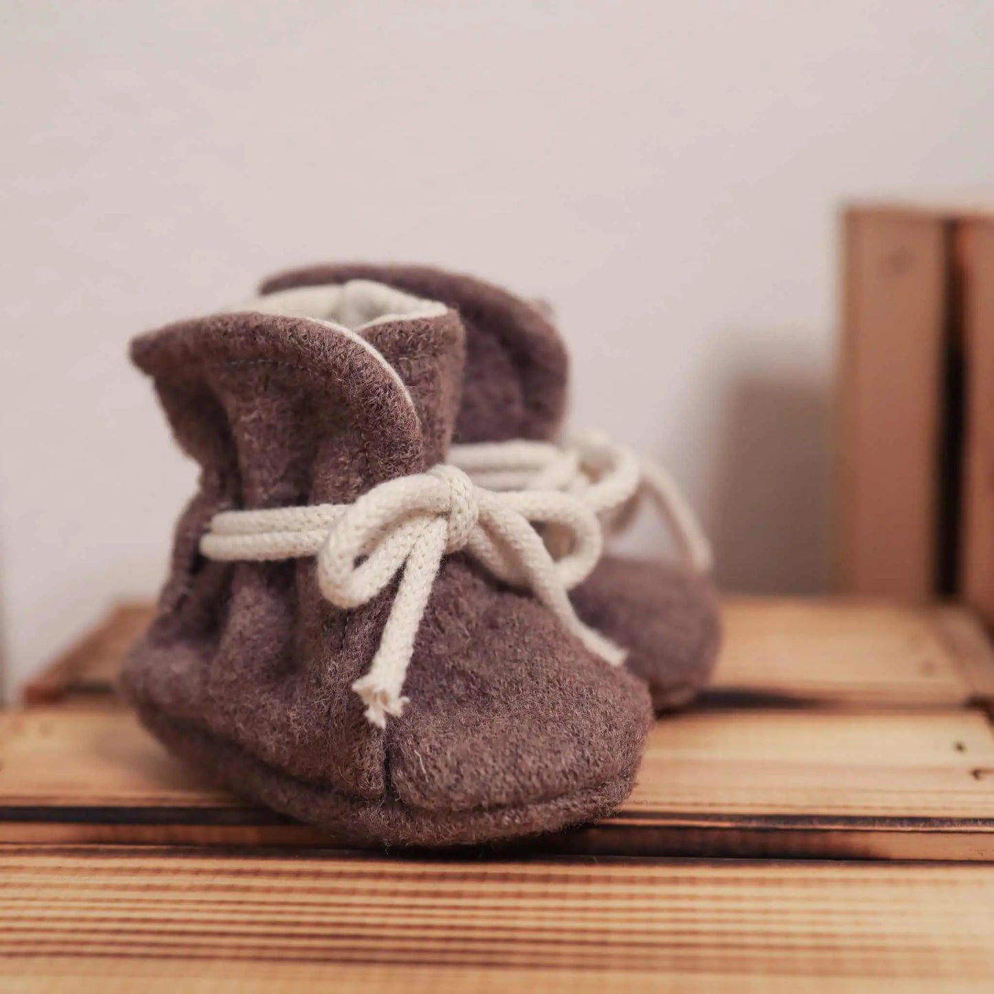Babyschühchen aus Wollwalk in taupe on wooden surface.