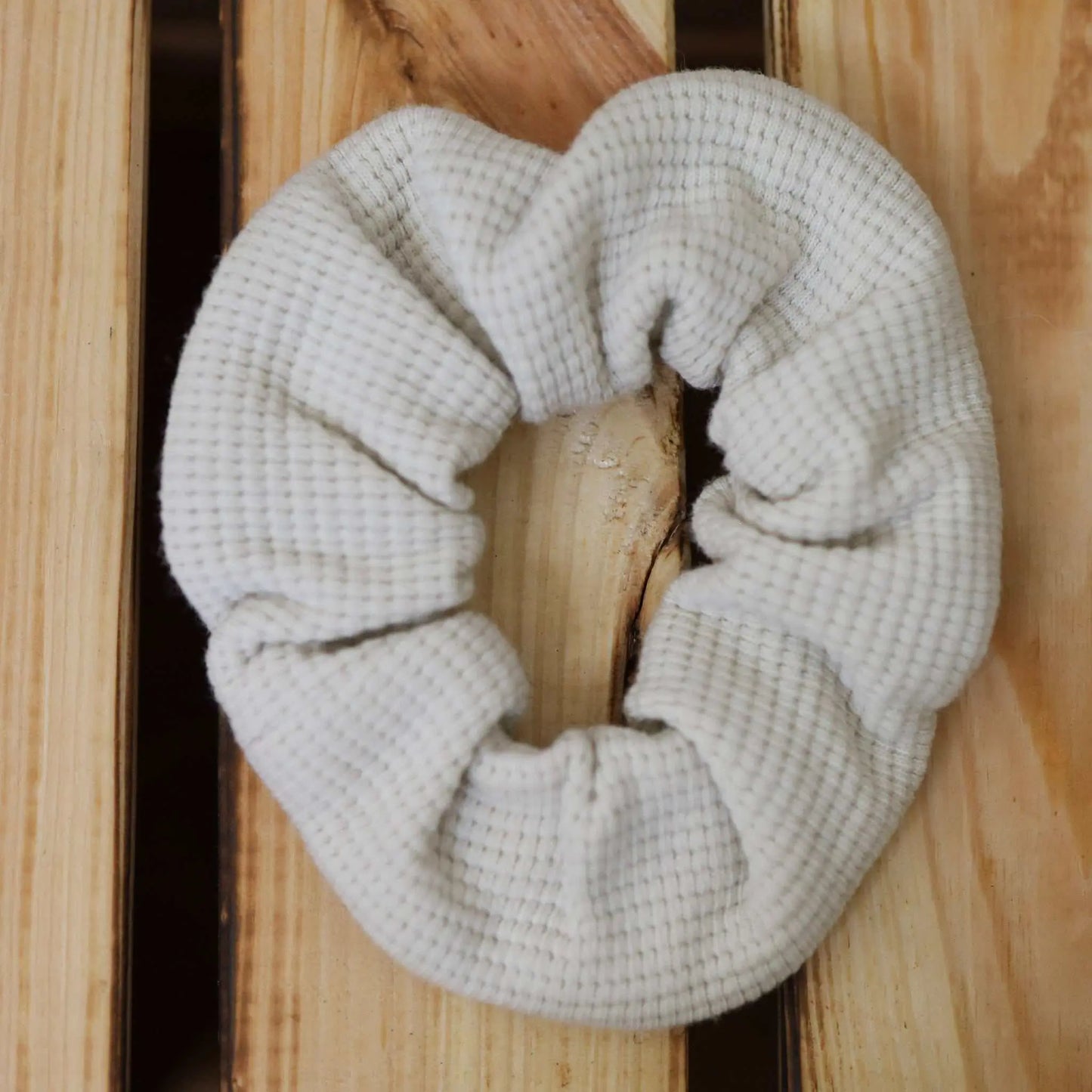 Scrunchie in ecru made from waffle jersey fabric on a wooden surface.