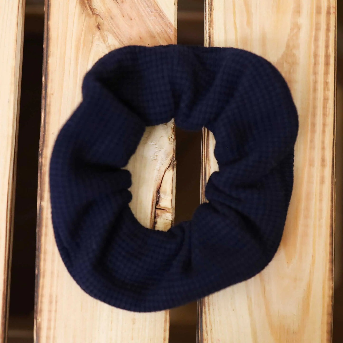 Navy waffle scrunchie on wooden surface.
