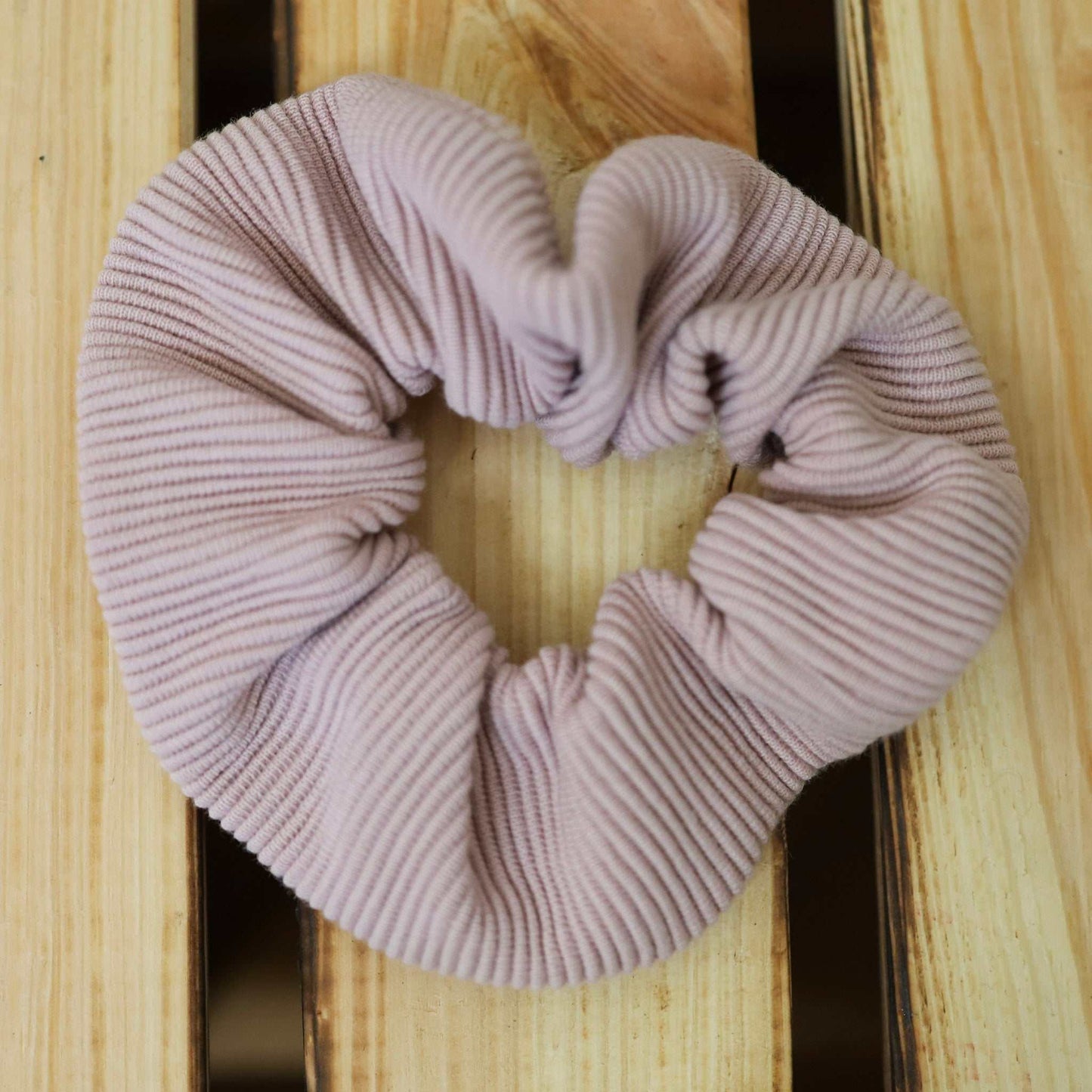 Scrunchie in nude rosa made from jersey rib fabric on wooden surface.