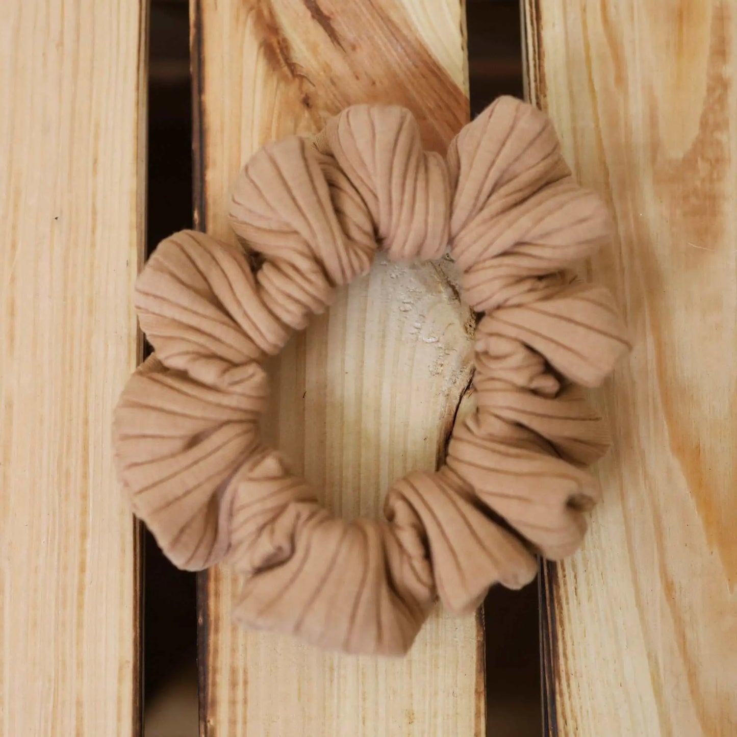 Scrunchie schmal in camel on wooden background, versatile hair accessory.