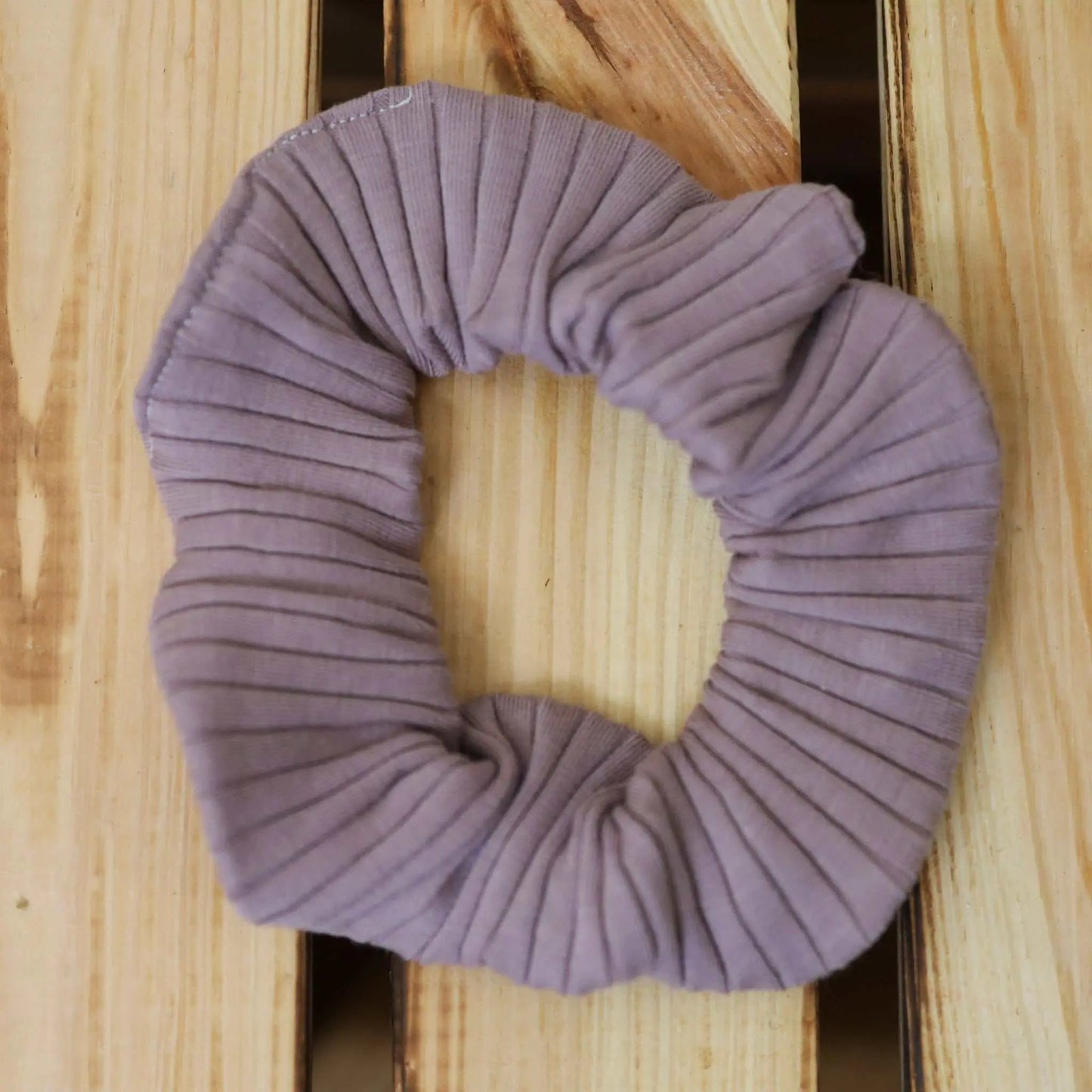 Scrunchie in flieder made from jersey fabric on wood surface.
